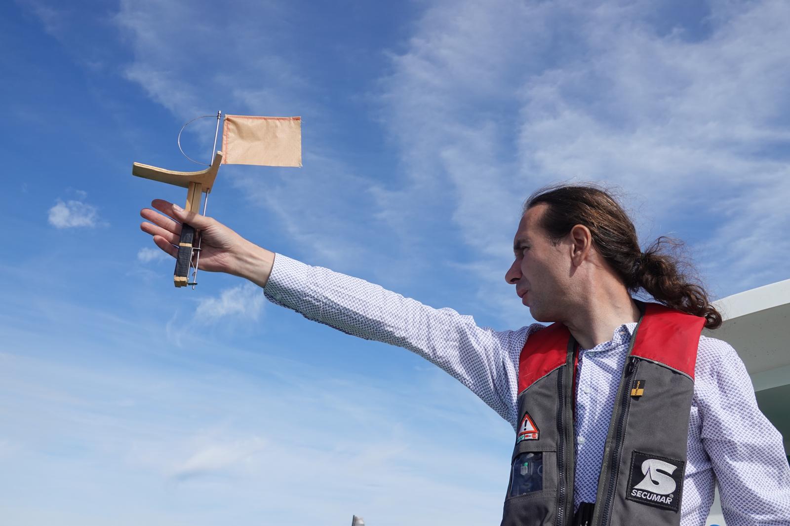 An Bord wird eine Windfahne gegen den blauen Himmel hochgehalten