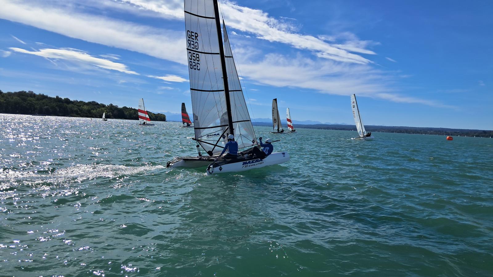 Formula-18-Katamaran GER 358 am Wind auf dem Ammersee, dahinter die Flotte und die Alpenkette